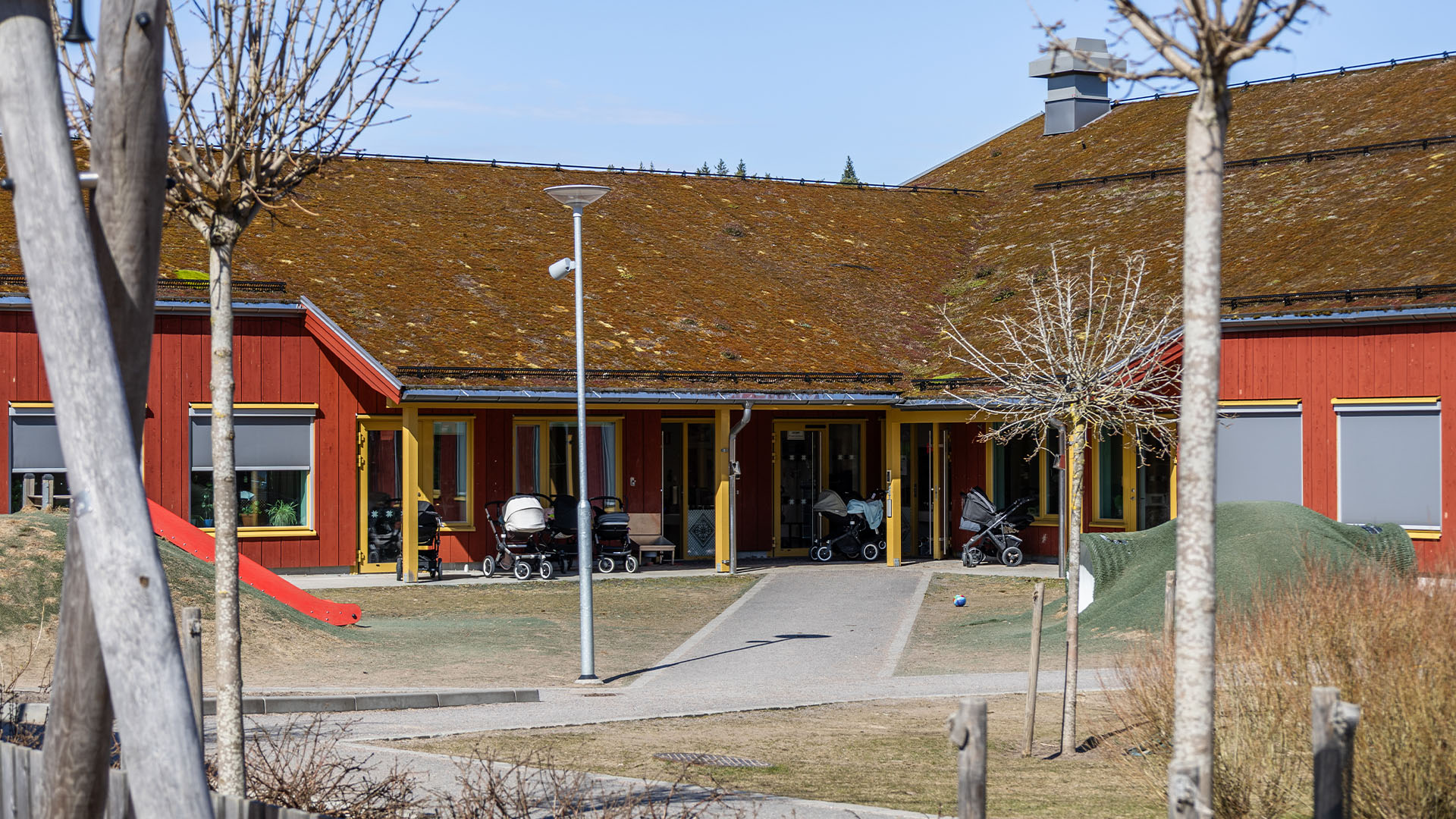 Fasad på Toppluvan förskola sett från gården med barnvagnar utanför.