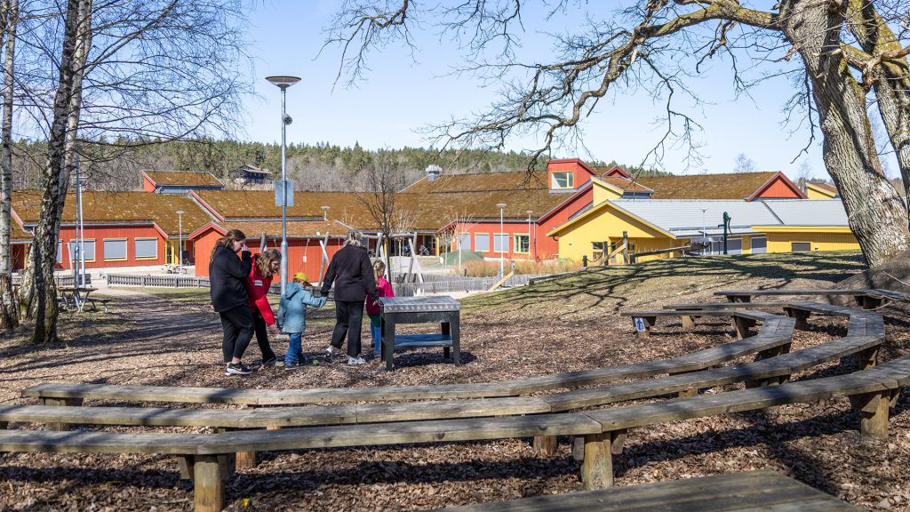 Förskolelärare med barn som går mot förskolan Toppluvan ifrån gården.