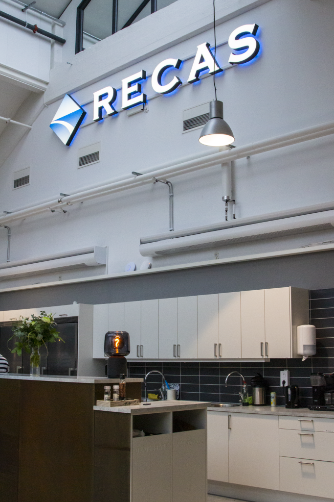 I vyn mot taknock i köksdelen syns Recas logotyp belyst i stort format på väggen.