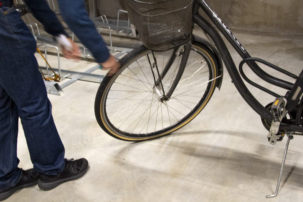 Bild där halva kroppen av en man syns som lagar en cykel