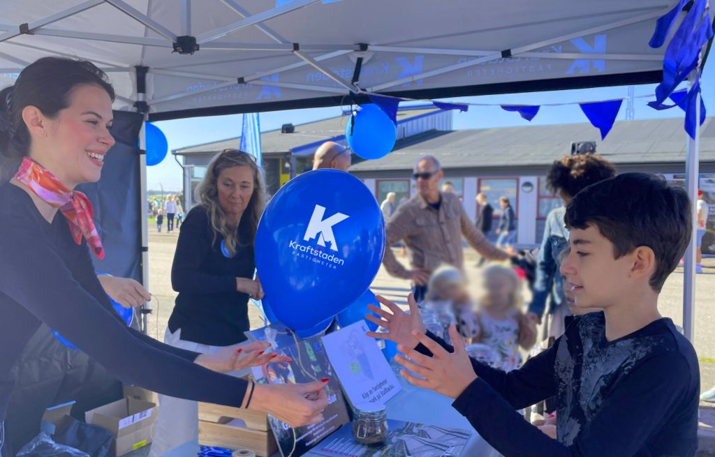 Medarbetare räcker över ballong till en ung kille i eventtält