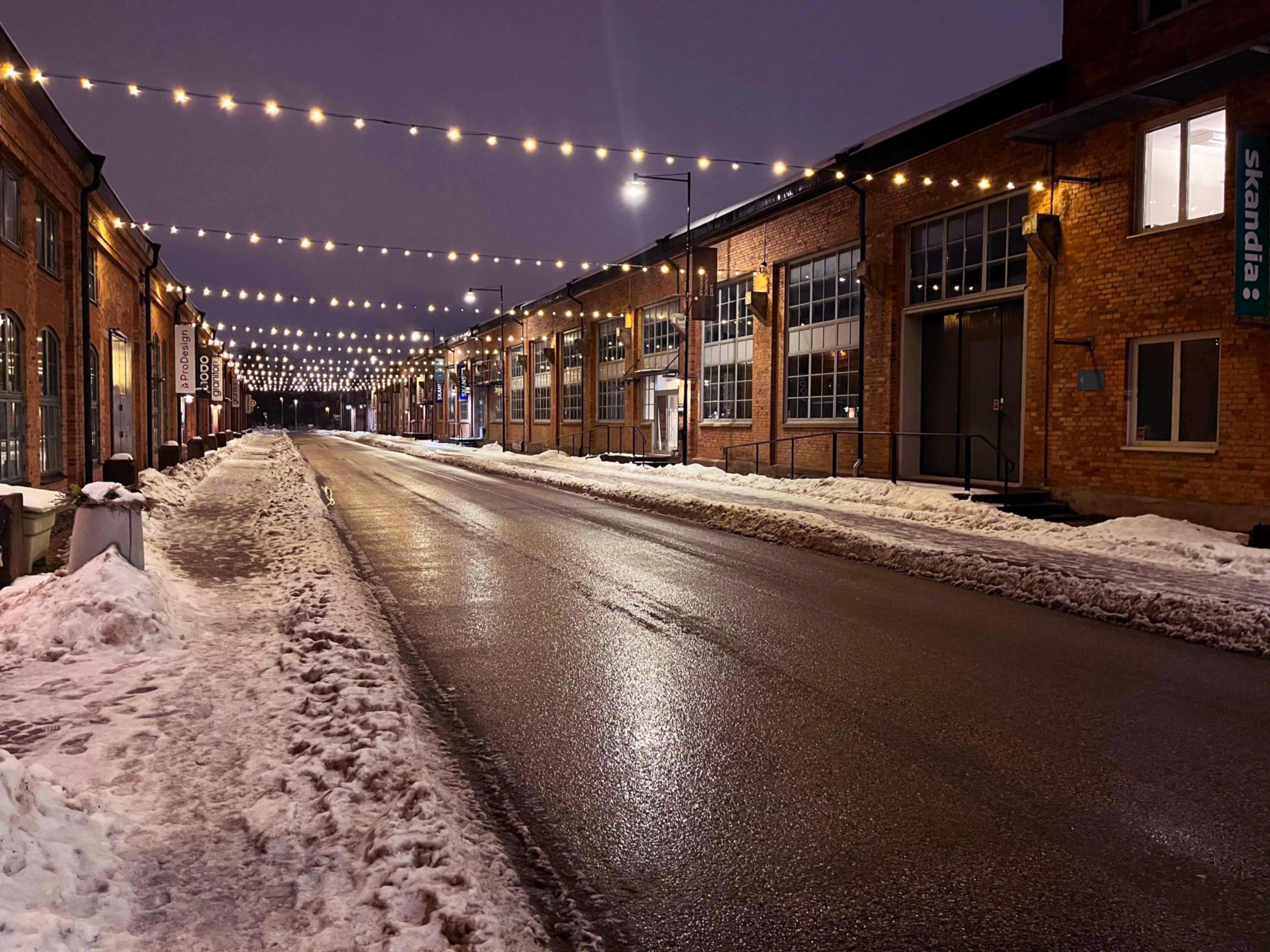 Ljusslinga över Nohabgatan. Plogad snö på gångbanorna. Natthimmel.