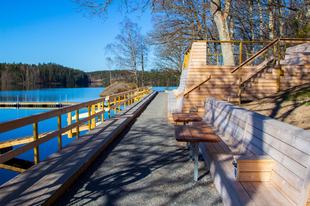 Mysig badplats med bord och bänkar.