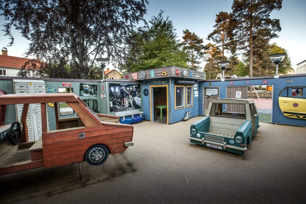 Lekplats med bilar i rött och blått bland tallar